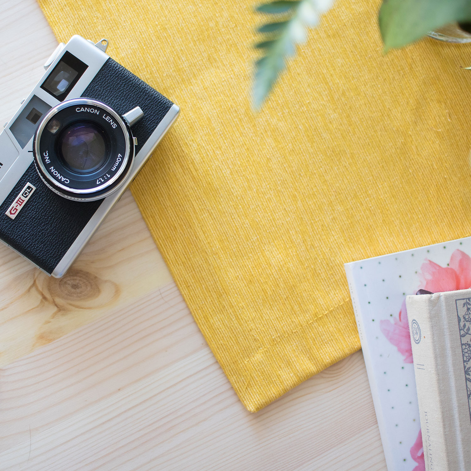 Photo of a camera laying on top of a desk with a bright yellow cloth underneath it