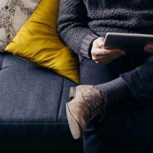 Photo of person sitting on a couch using a tablet