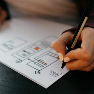 Photo of a person drawing website wireframes on white paper with a pen