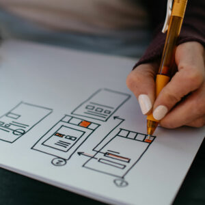 Closeup photo of a woman's hand sketching a website wireframe in ink